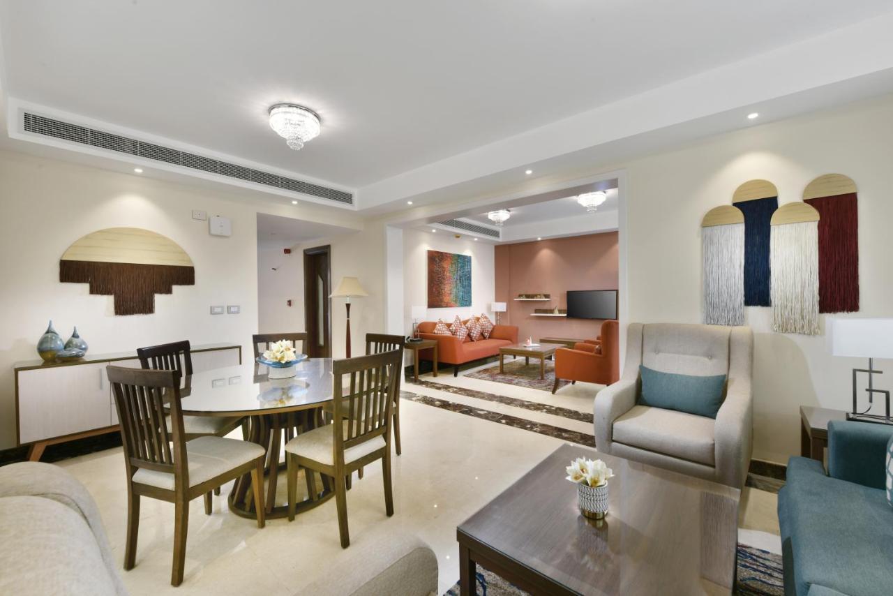 Tolip Resort El Galala Majestic Ain Sukhna Buitenkant foto The photo shows a modern living room space that is elegantly designed. It features a seating area with a comfortable sofa and armchairs, complemented by a decorative coffee table. There is a dining table with several wooden chairs, providing a cozy a