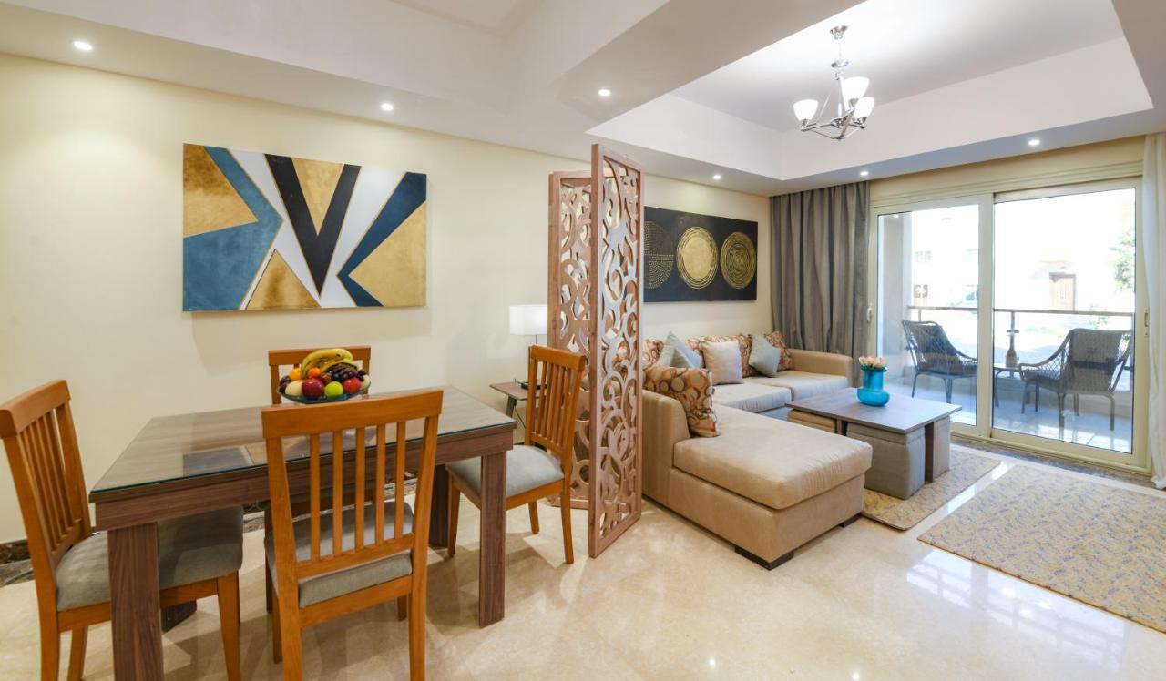Tolip Resort El Galala Majestic Ain Sukhna Buitenkant foto The photo shows a modern and stylish interior of a living space. It features a seating area with a plush sofa and decorative cushions, complemented by a wooden coffee table. There is a dining table with wooden chairs nearby. 

On the walls, there are