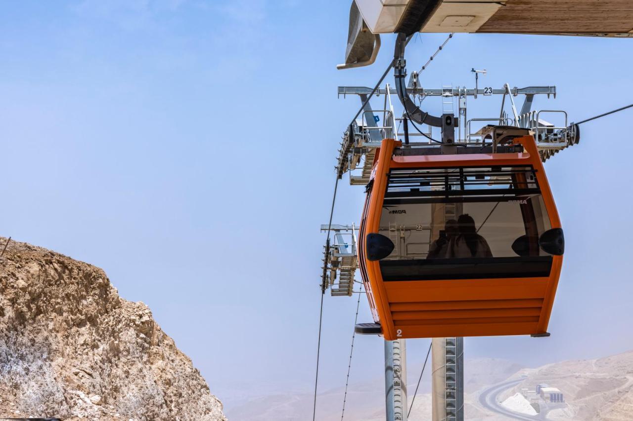 Tolip Resort El Galala Majestic Ain Sukhna Buitenkant foto The photo shows an orange gondola or cable car hanging on a cable system. The gondola appears to be suspended in the air above a rocky landscape, with a clear sky in the background. There are supporting cables and structures visible, indicating that 