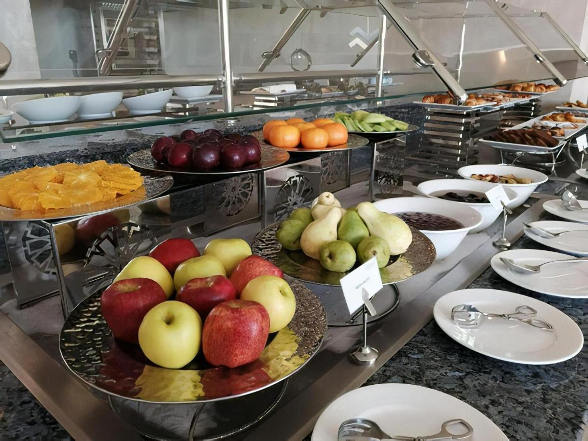 Tolip Resort El Galala Majestic Ain Sukhna Buitenkant foto The photo displays a buffet setup featuring an assortment of fresh fruits arranged on several tiered trays. There are red and green apples, pears, grapes, and oranges. Adjacent to the fruit display, there are several bowls containing various other fo