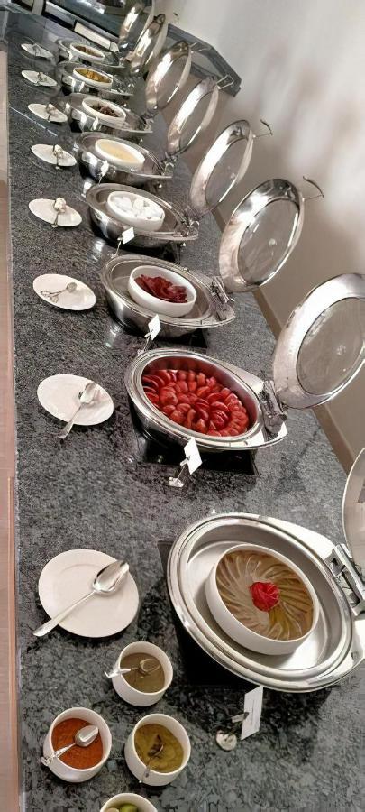Tolip Resort El Galala Majestic Ain Sukhna Buitenkant foto The photo shows a buffet setup featuring multiple metal serving trays on a dark granite countertop. One tray contains circular slices of food, possibly sausages or a similar dish, while another bowl holds what appears to be red food items, though it'