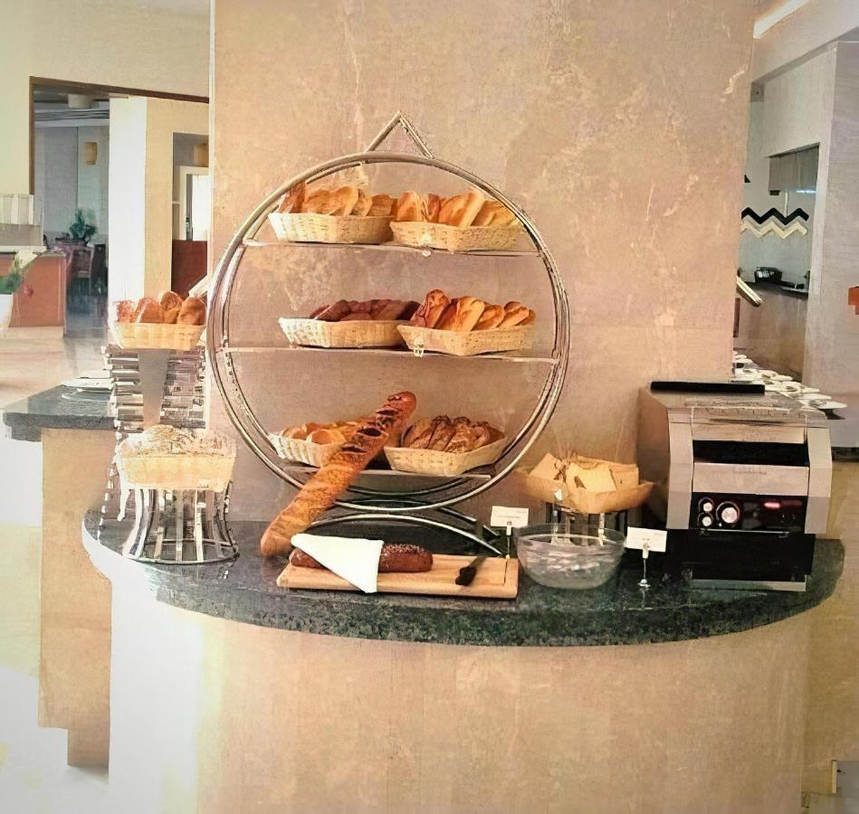 Tolip Resort El Galala Majestic Ain Sukhna Buitenkant foto The photo shows a display of various types of bread and pastries arranged on a countertop. There are several baskets stacked on a circular stand, filled with different baked goods like croissants and rolls. A long baguette is placed horizontally on a