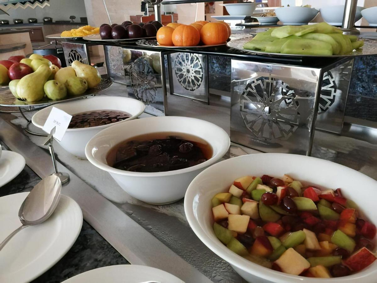 Tolip Resort El Galala Majestic Ain Sukhna Buitenkant foto The photo shows a buffet-style arrangement of various fruits and fruit dishes. In the foreground, there are several bowls containing different types of fruit. One bowl has a fruit salad made with diced apples, green apples, and possibly other fruits.